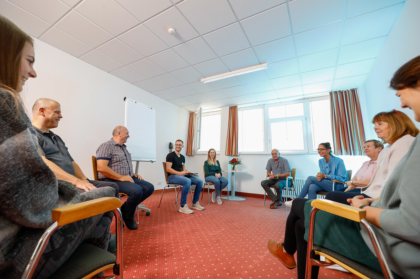Gruppentherapie, Stuhlkreis mit lächelnden, freundlichen Menschen